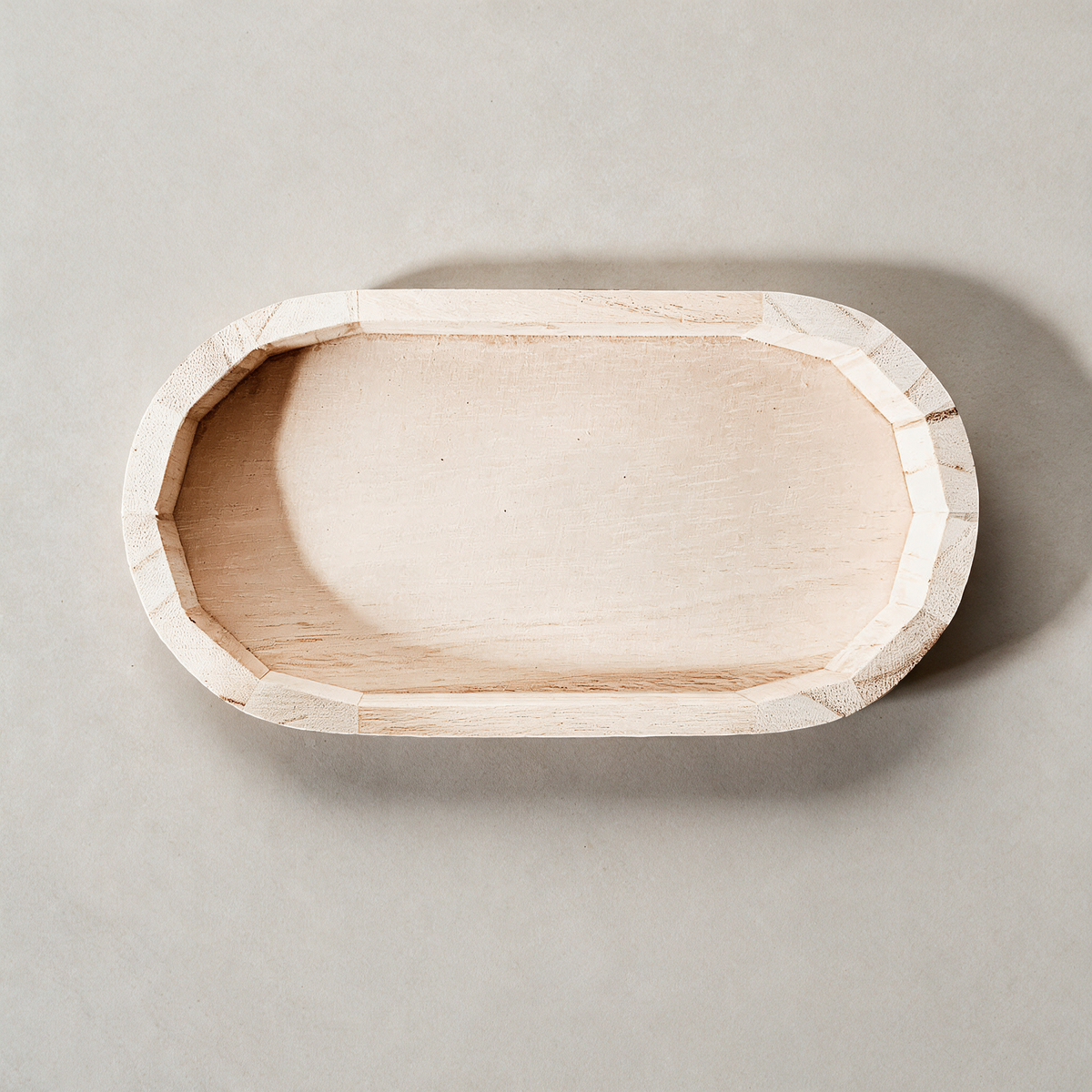 Wooden catch-all tray on a warm grey studio background
