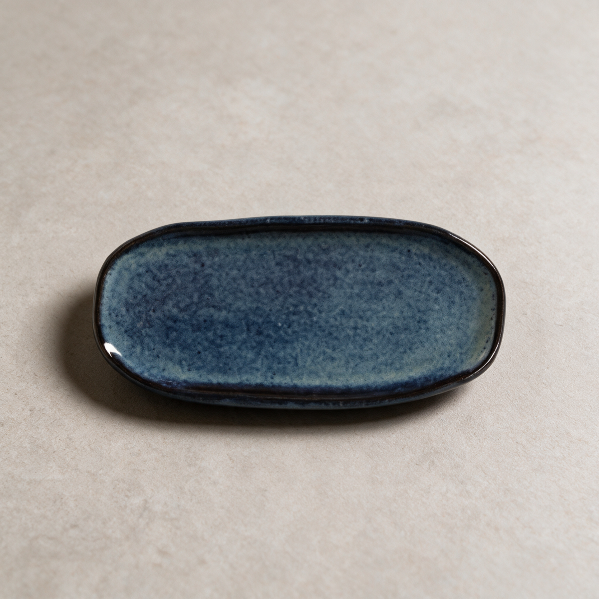 Blue stoneware oval dish on a warm grey studio background