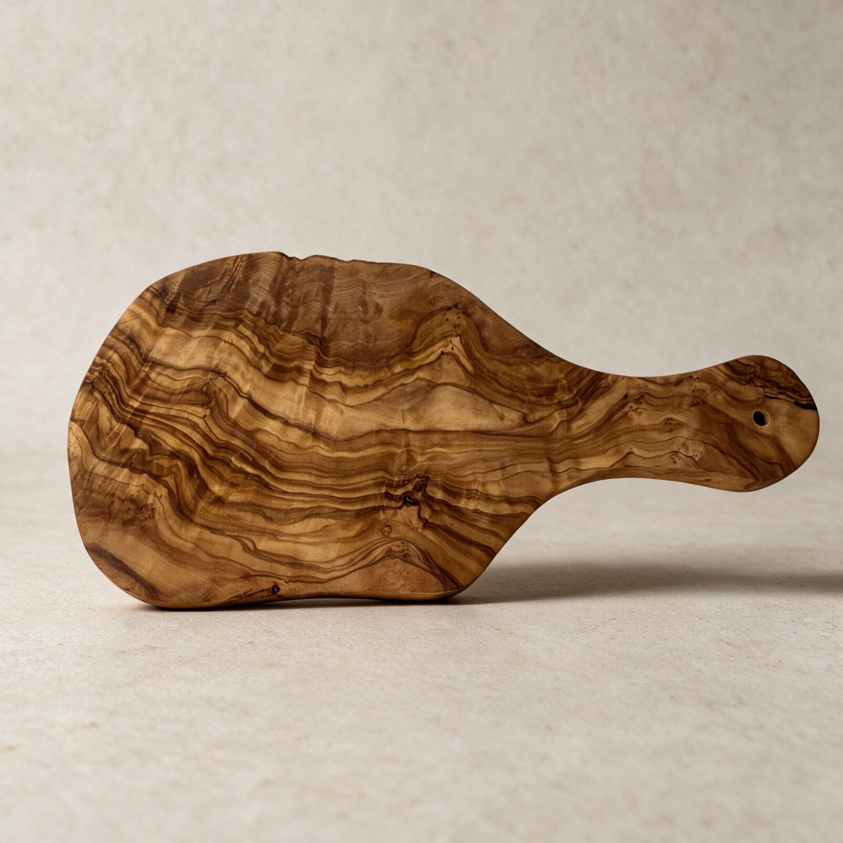 Olive wood cutting board on a warm grey studio background