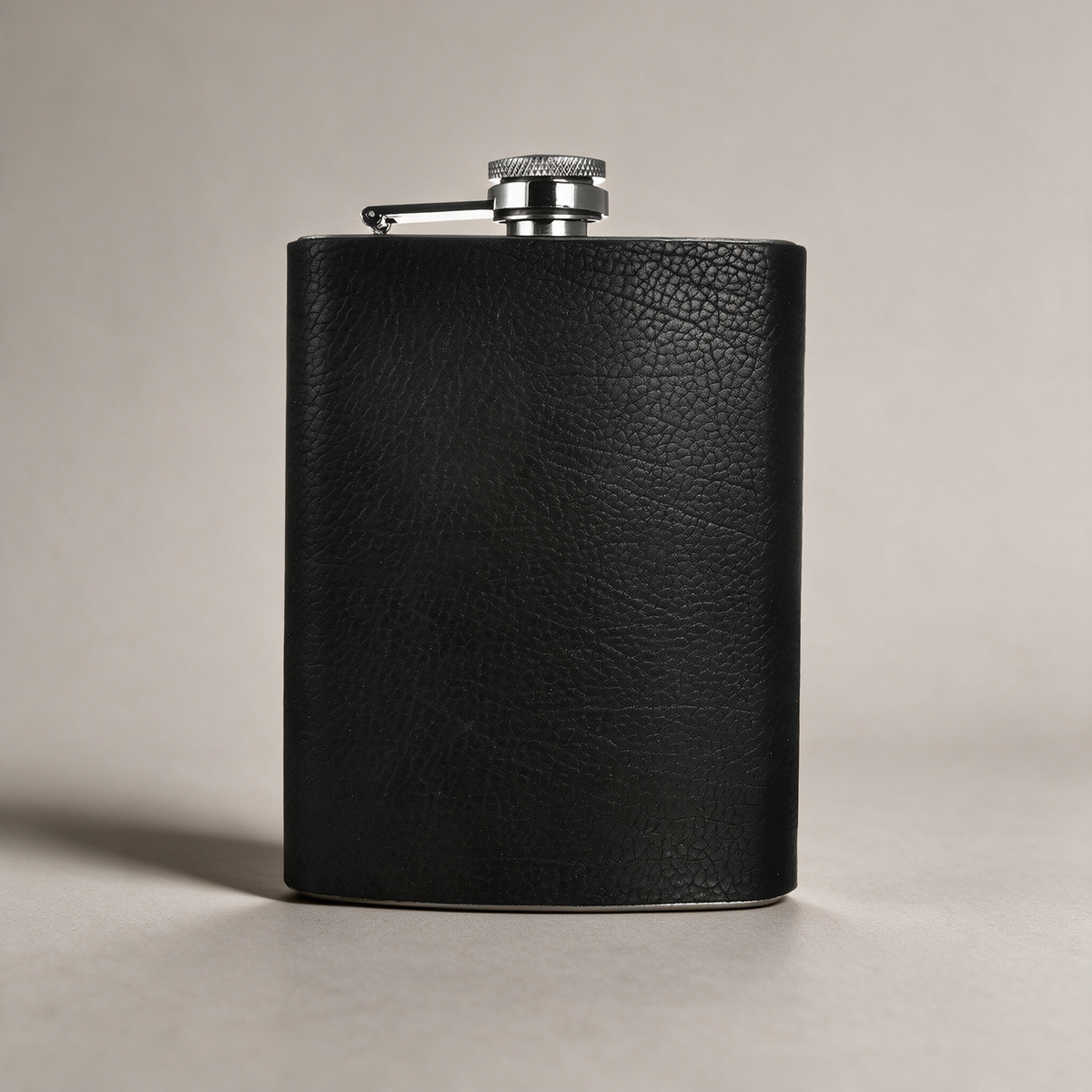 Leather-wrapped flask on a warm grey studio background