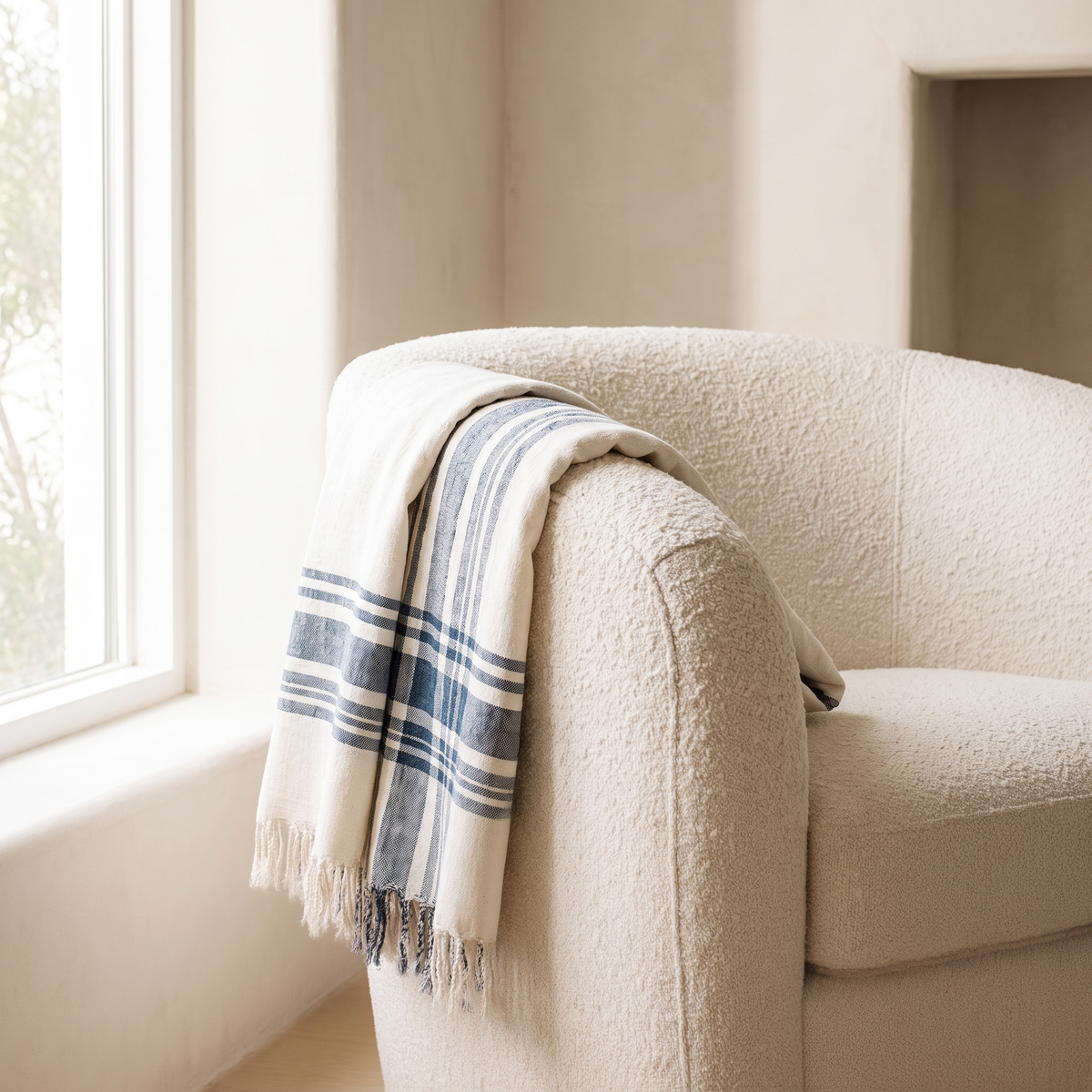 Cabin Hatch Cotton Throw over the arm of a boucle chair by a window