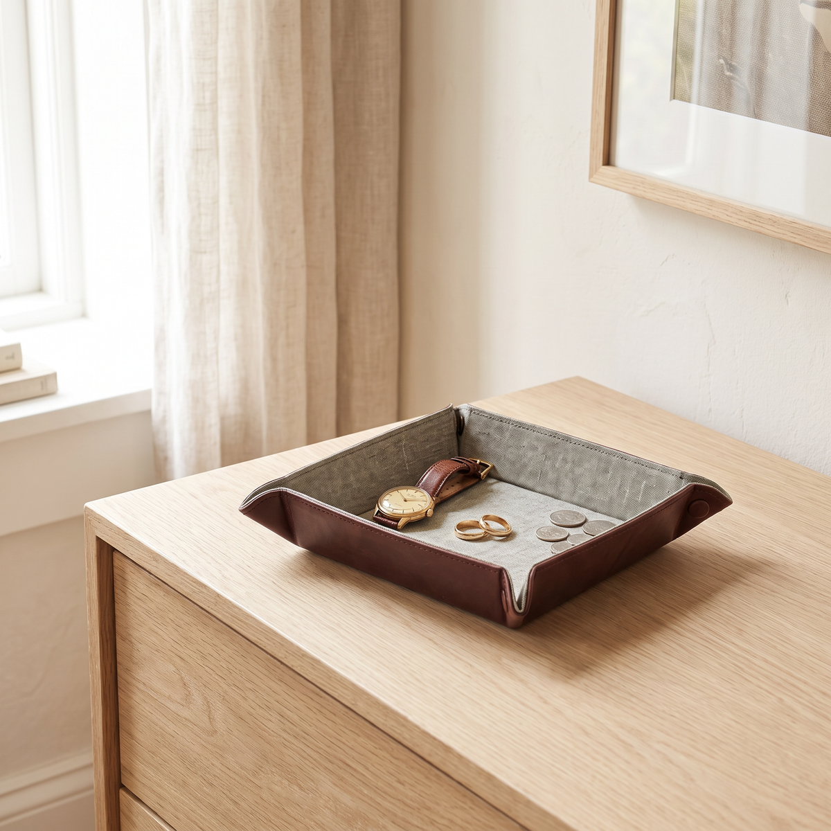 Foldable Leather Valet Tray on a chest of drawers holding a watch, rings and coins