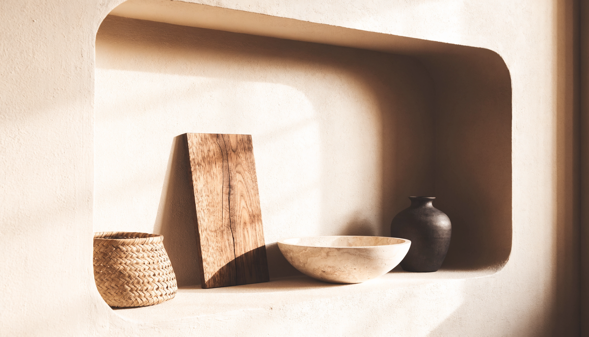 A niche of chosen objects: walnut board, woven basket, travertine bowl and ceramic vessel