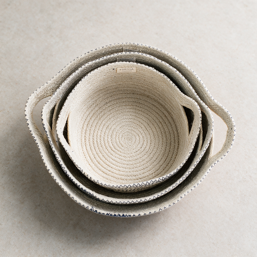 Nested woven fruit bowls on a warm grey studio background