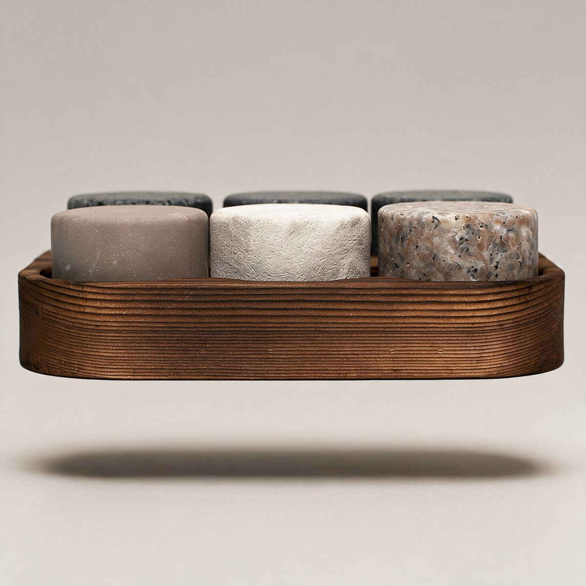 Whiskey chilling stones in a wooden tray on a warm grey studio background